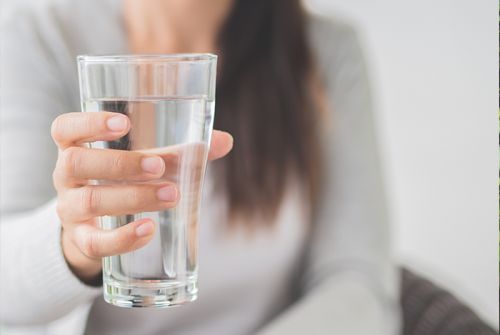 Frau hält Glas mit Wasser in die Kamera